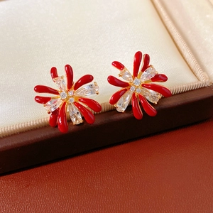 Macro detail of red petal stud earrings with white zircon centers in 18k gold plating