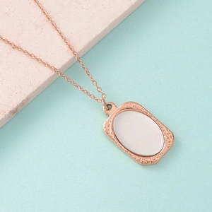 Detail van een roségouden rechthoekige hanger met getextureerde randen op een stenen voet