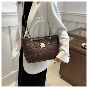 Detail of dark brown quilted shoulder bag with gold chain strap and metallic buckle