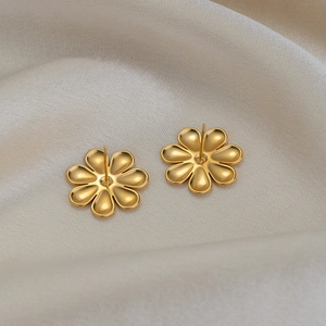 Minimalist 18K gold plated flower stud earrings in 925 silver on beige silk fabric