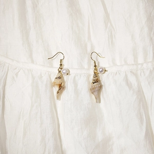 Detail of gold seashell earrings with natural mother of pearl and small pearl accents
