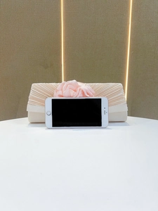 Light pink pleated evening clutch bag with elegant fabric flower detail close up shot.