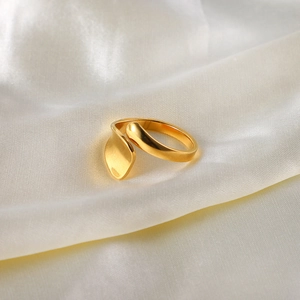 Nahaufnahme eines 18K vergoldeten, unregelmäßigen geometrischen Rings auf weißem Seidenstoff