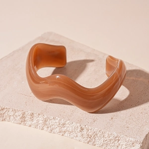 Macro shot of wavy brown acrylic cuff bracelet with marble texture on stone base
