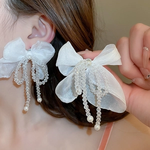 Gros plan détaillé de boucles d'oreilles nœud en tulle avec pampilles perlées