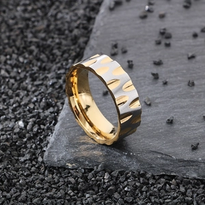 Macro detail of two-tone stainless steel ring with silver gear texture and gold inner band