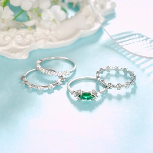 Detalle del juego de cuatro anillos apilables con gema verde esmeralda y diseño de hoja de olivo