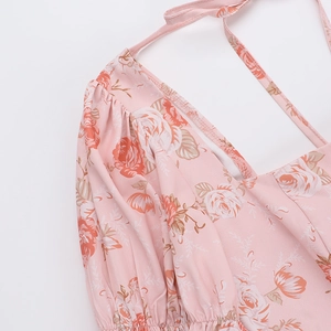 Détail de l'imprimé floral rose sur robe en mousseline rose avec licou et épaules volantées