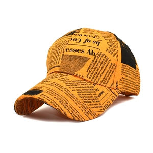 Orange baseball cap with black newspaper print pattern and classic curved brim style