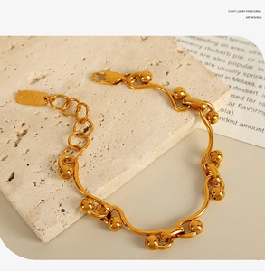 Macro view of gold-plated titanium steel beaded bracelet with Lucky engraved charm tag