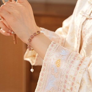 Detail of strawberry quartz beads and pearls bracelet on woman's wrist in elegant style