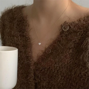 Close-up of golden 925 silver heart necklace with zircon pendant on model wearing sweater