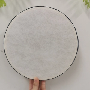 Circular white non-woven fiber filter element held by hand against a minimal background