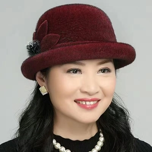 Close-up of wine red winter hat with leaf decor and black fur pompom for older women
