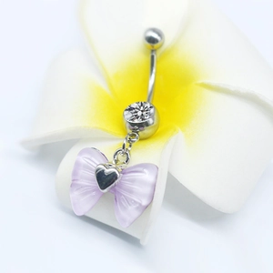 Macro detail of silver navel ring with purple bow pendant on a frangipani flower