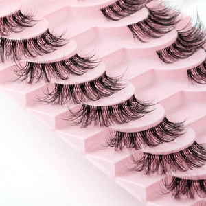 Detailed close-up of 10 pairs of dense curly black false eyelashes in a pink tray