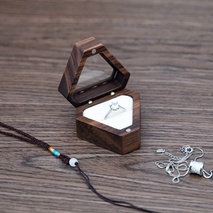 Macro view of a hexagonal brown wood jewelry box with glass lid and white cushion