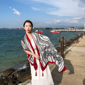 Ethnic red beach shawl with intricate patterns and tassels worn by the seaside