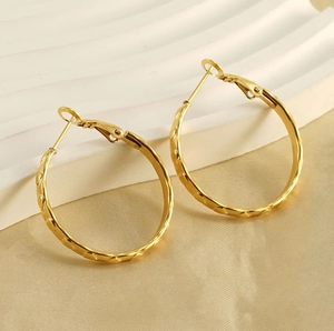 Dettaglio di orecchini a cerchio placcati in oro 18k con trama a cuore goffrata