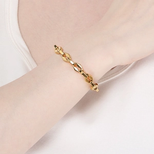 Détail d'un bracelet à maillons géométriques dorés épais porté au poignet pour un style urbain