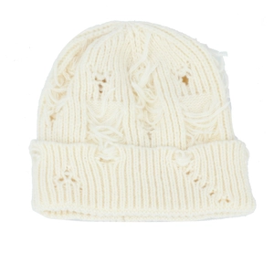 Detailed close-up of cream knit beanie featuring distressed holes and ribbed texture