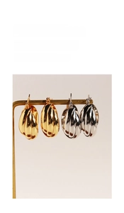 Macro detail of multi-layered oval geometric hoop earrings in gold and silver finish