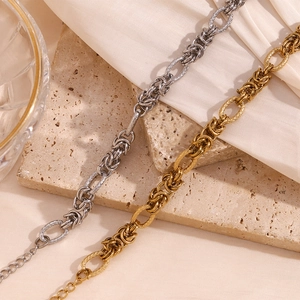 Detail of gold and silver knot chain bracelets on beige stone and silk background