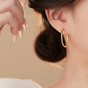 Polished gold circular hoop earring displayed on a model for a minimalist fashion style