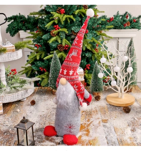 Détail d'un gnome de Noël avec bonnet en tricot rouge sur une surface en bois enneigée