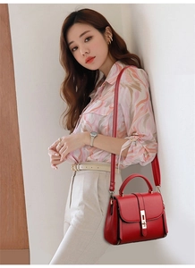 Detailed view of red leather crossbody bag with gold metallic lock and side zipper