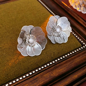 Detail of silver hollow flower earrings with diamond center on green velvet display