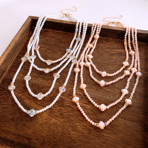 Detail of multi-layer pearl necklace with crystal beads and golden clasp in wood tray