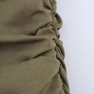Dettaglio macro del tessuto in lino verde oliva dell'abito midi con trama a pieghe