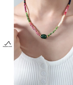 Detail of colorful beaded necklace with green oval stone and stainless steel components