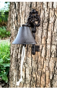 Detail of vintage cast iron door bell with key-shaped bracket and white cotton rope