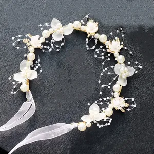 Detail eines Blumen-Haarbands mit weißen Seidenblumen, Perlen und Organza-Bändern