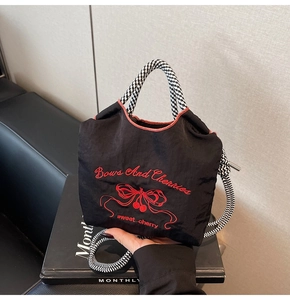 Detailed red cherry embroidery and weave handles on a black nylon tote shoulder bag