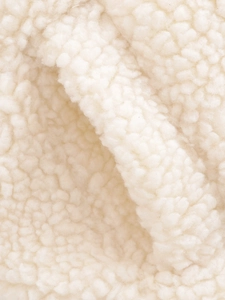 Close-up of soft cream faux shearling fabric texture for fashion waistcoat detail