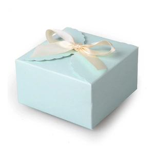 Light blue square paper gift box with beige ribbon bow and wavy cut-out design