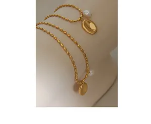Detail of gold oval pendant necklace with freshwater pearl and tiny bead chain