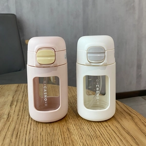 Detail showing two portable straw water cups in pink and white on a wooden table