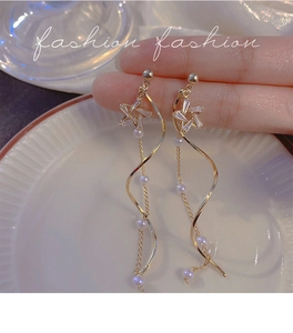 Macro detail of gold star earrings featuring cubic zirconia and elegant pearl tassels