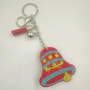 Detail of red bell keychain with colorful rhinestones, silk tassel, and silver bell charm