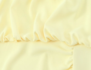 Macro detail of yellow midi dress fabric showing delicate pleats and fine texture