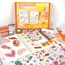 Flat lay view of a DIY journal set featuring scrapbook stickers and orange stationery items