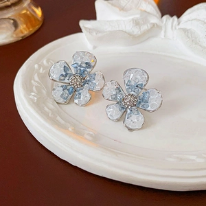 Close-up of blue crystal flower earrings with ice-crack texture and small diamond core
