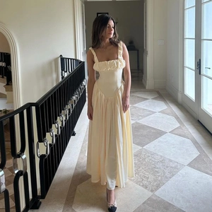 Detailed view of the sleeveless yellow long dress featuring ruffled straps and pleated hem