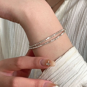 Close-up of double-layer S925 sterling silver beaded bracelet on a textured background