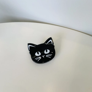 Close-up of a glossy black and white cat-shaped Halloween hair claw on white background