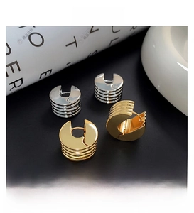 Macro detail of gold and silver hoop earrings with textured horizontal grooved finish